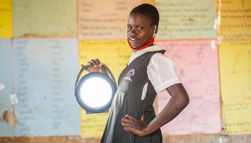 A girl holding a solar lamp provides an example of how even as the COVID crisis in Africa grows, BrightLife uses sustainable solar lighting to empower women and girls.