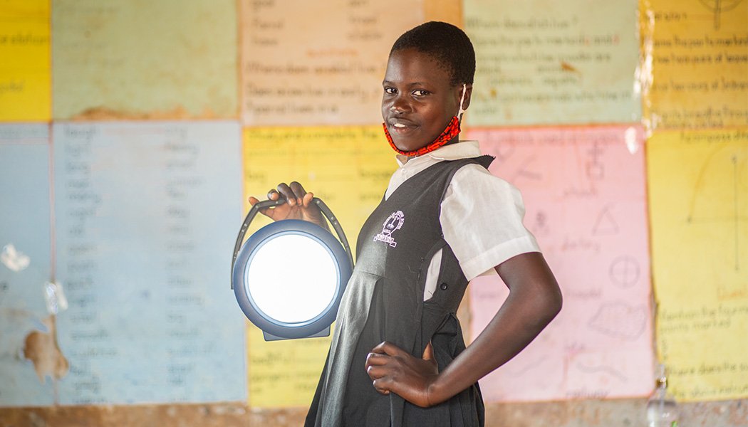 A Female Student Stands with a Solar Lamp