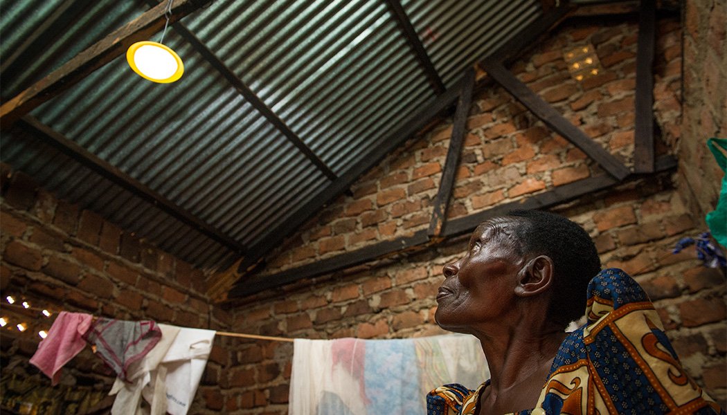BrightLife Client Margaret Nankonge Looking at her Solar Home System