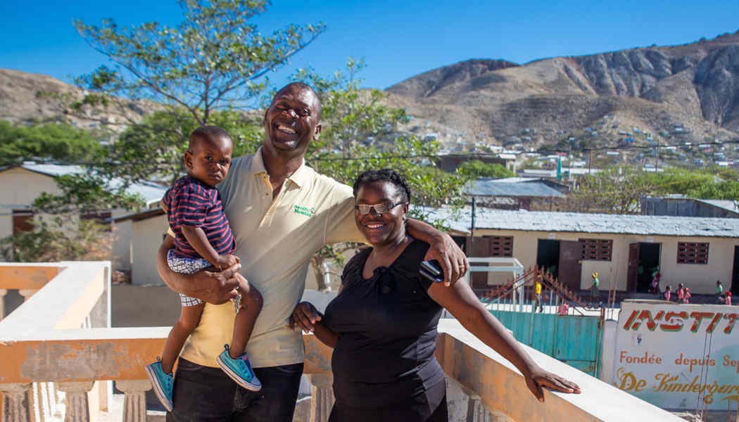 Annesse Aristild and Kerlande Toussaint and their youngest child in front of their school in Gonaives, Haiti