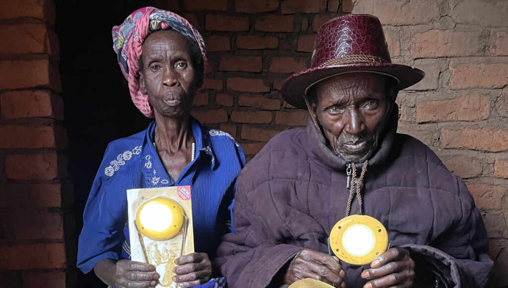 Flavia and Esaya hold the solar lights that they received through FINCA's Mwangaza project.